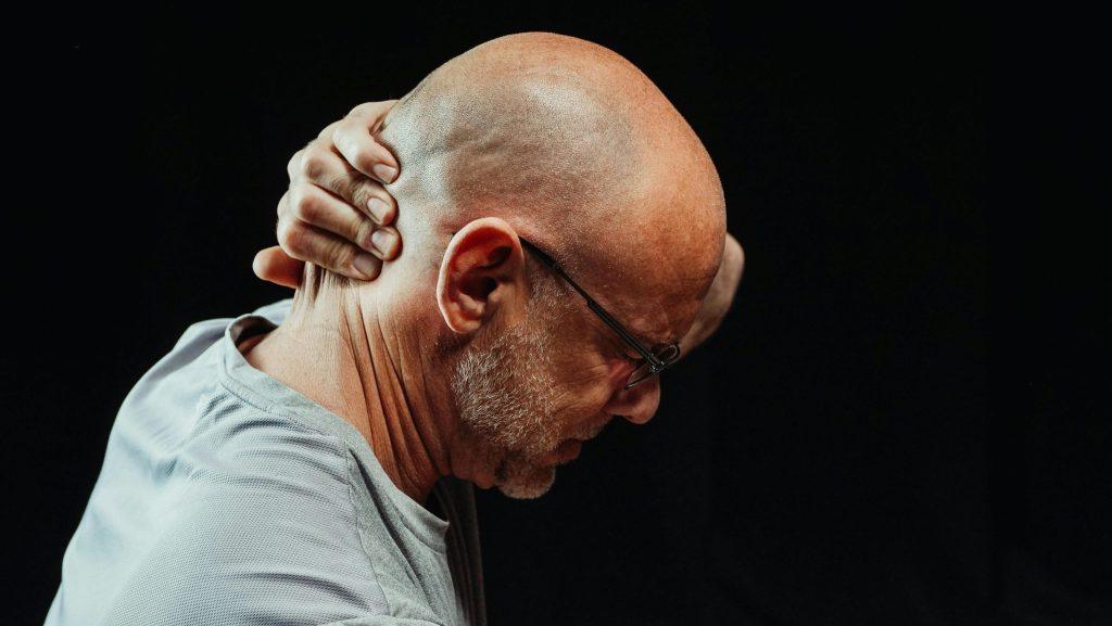 Man holding back of neck from arthritis pain