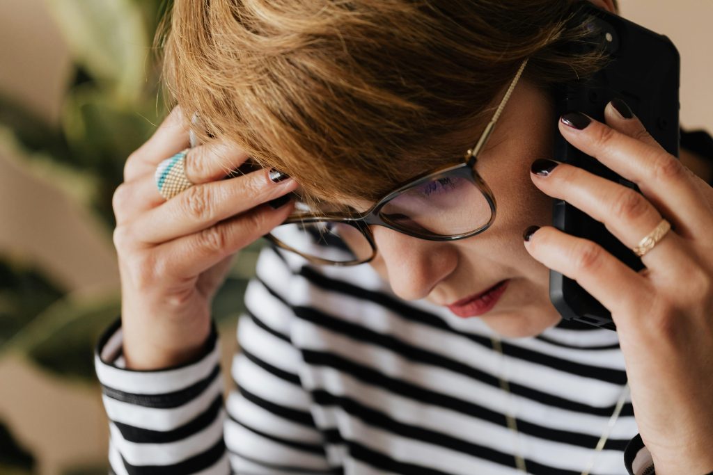 Woman holding her head while talking on the phone