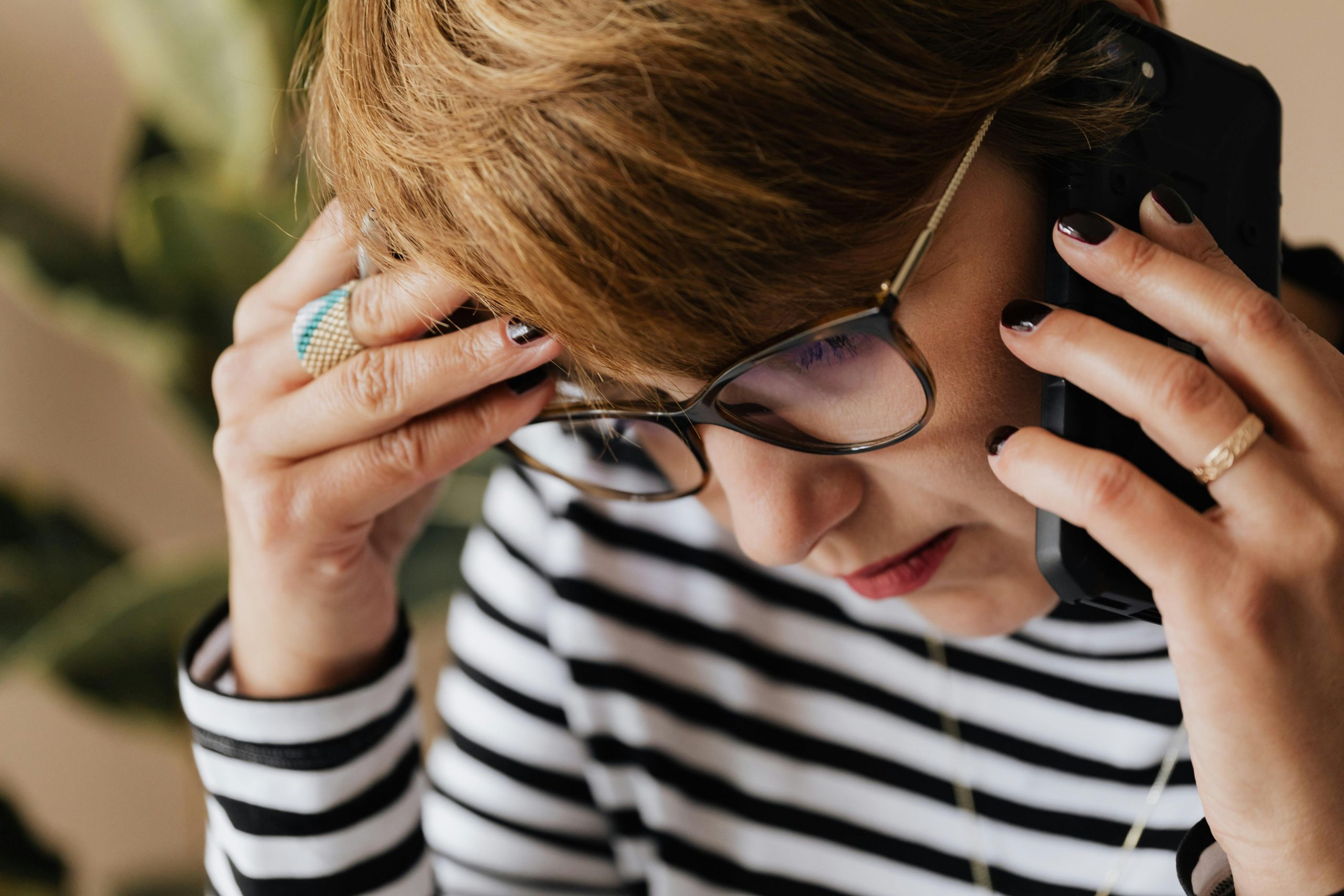 Woman holding her head while talking on the phone