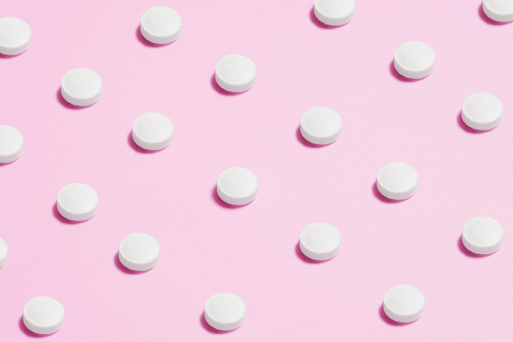 Pills lined up on a pink background