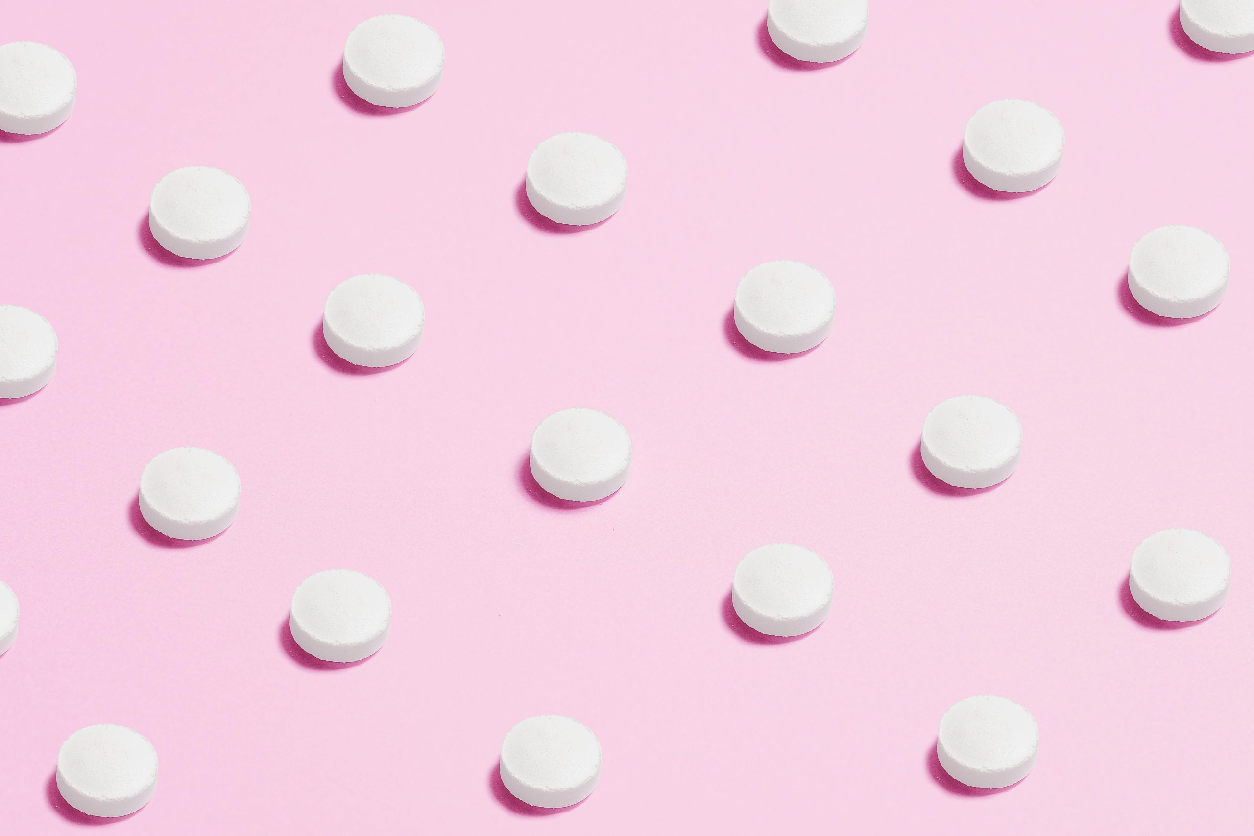 Pills lined up on a pink background