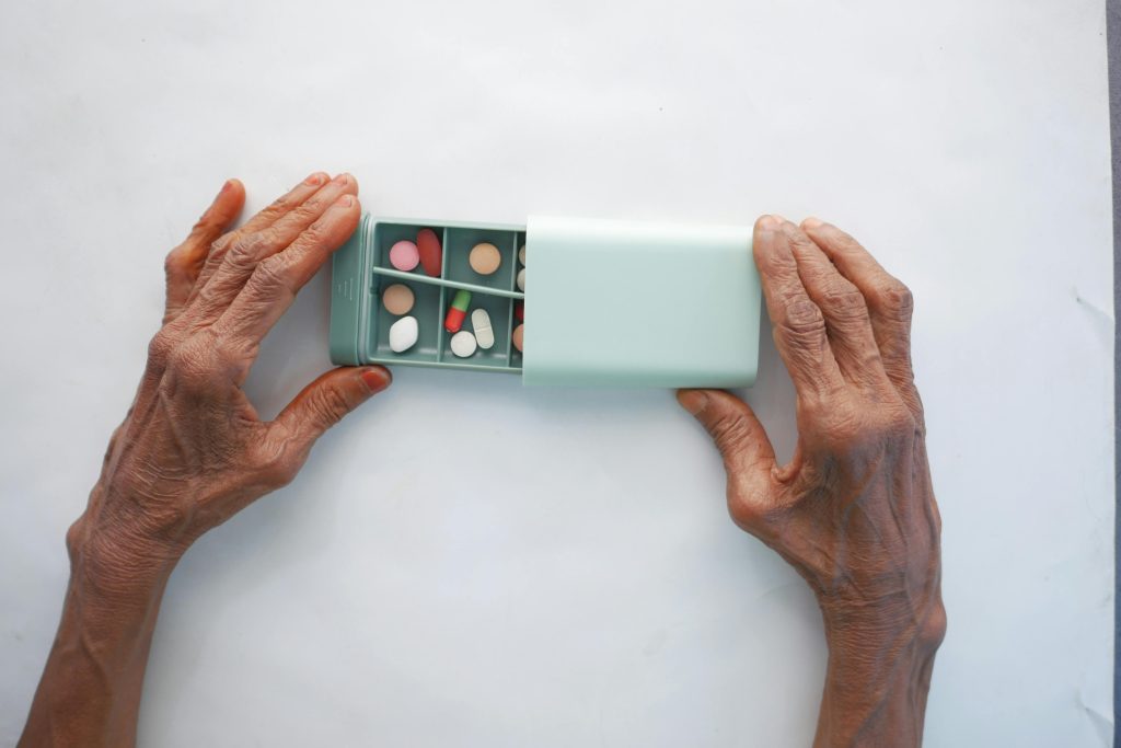 Person with arthritic hands opening a pill box