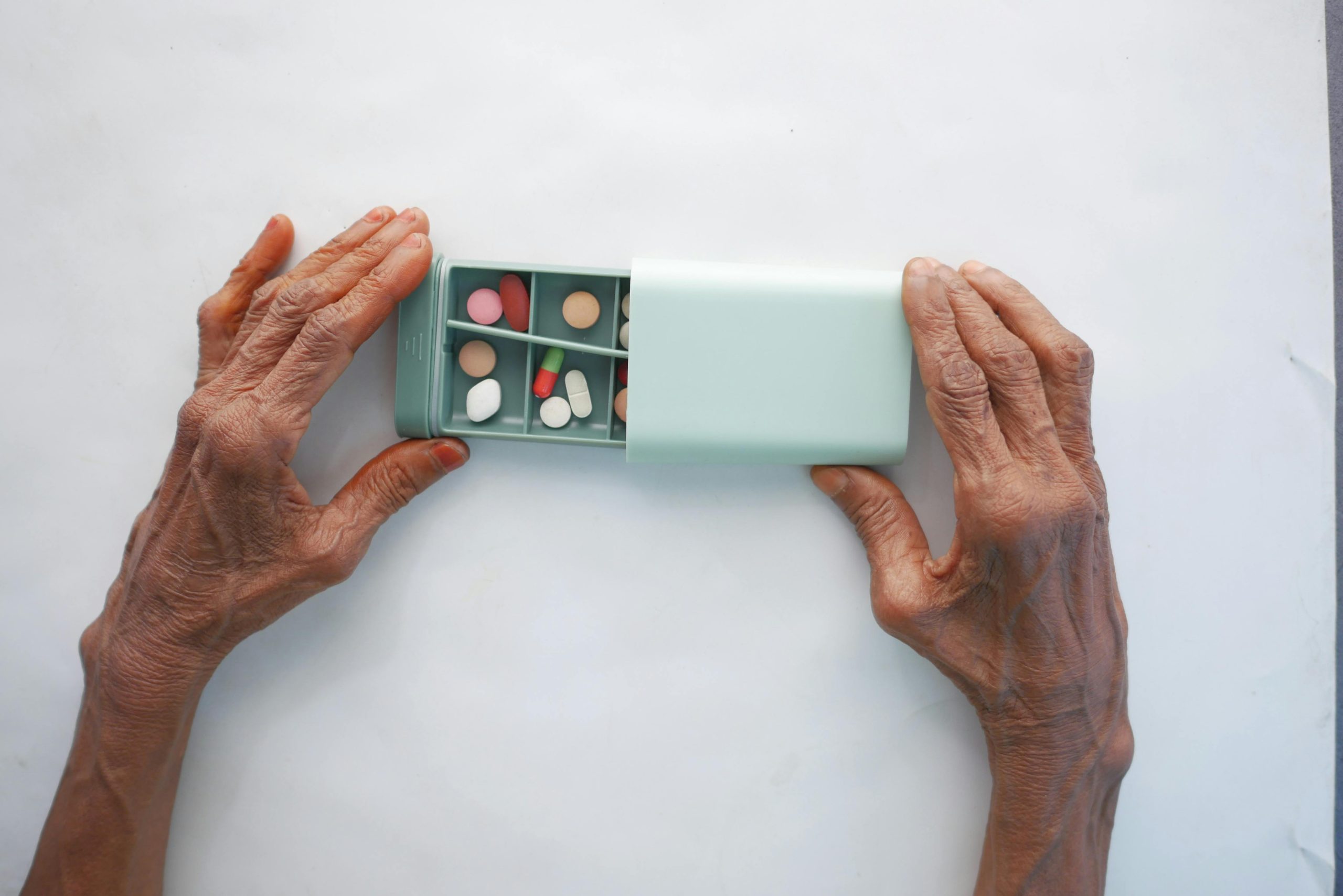 Person with arthritic hands opening a pill box